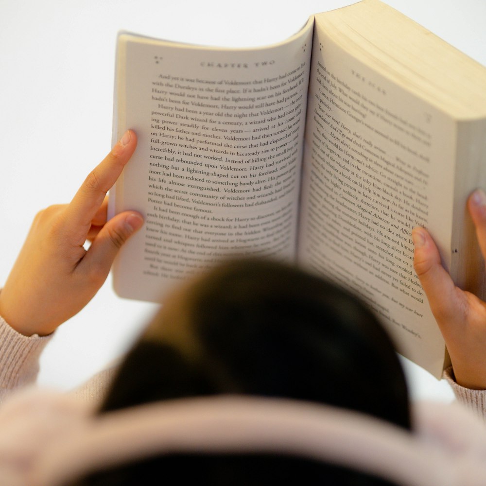 امرأة بملابس بيضاء تقرأ كتابا بهدوء تحت ضوء الصباح