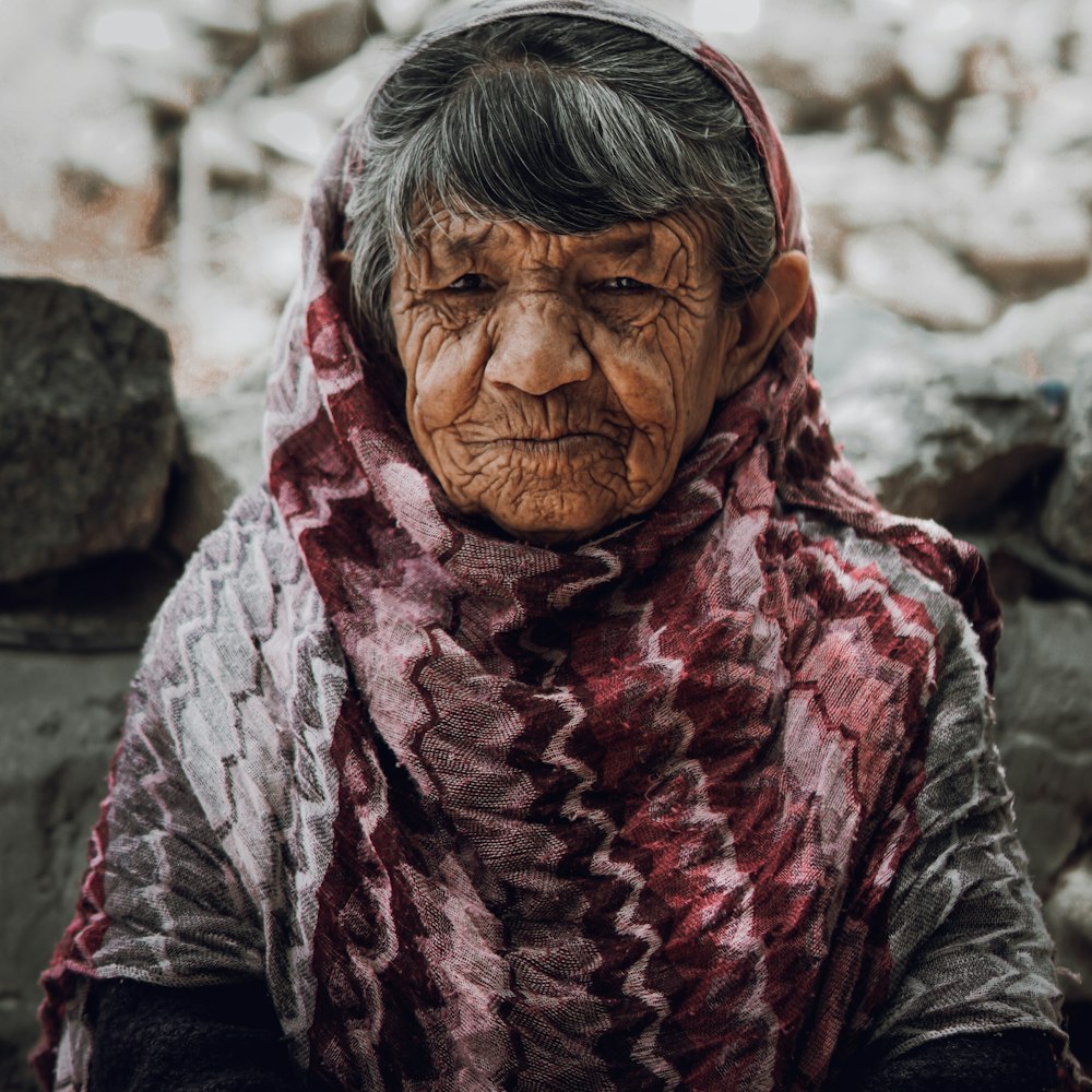 امرأة عجوز بوشاح ووجه متجعد يحمل ملامح الحزن والقوة
